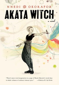 A book cover. The writer's name is at the top in small, red font, with a red circle in the middle. The title "Akata Witch" is directly below this in large, black font. Below this, lower right, in smaller, black font, the phrase "a novel". Large art of a young woman stretches across the centre of the book. She is wearing a black, short sleeved shirt, dark grey pants, and black shoes. In her left hand, she holds a dagger. The dagger is pointing down, and streaks of various bright colours seem to be coming out of the tip. /end