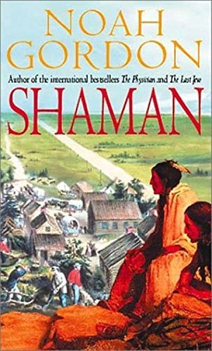 A book cover. The author's name "Noah Gordon" is written at the top of the cover in large yellow capitals. Small black text directly under it reads "Author of the international bestsellers 'The Physician' and 'The Last Jew'". The title of the book "Shaman" is written below this in large red capitals. The background shows art of a small village next to a field. There's a long road separating the filed and village, and people are working in the village. In the foreground of the cover, down the lower right side, art of two Native Americans sitting on red rocks overlooking the village. /end