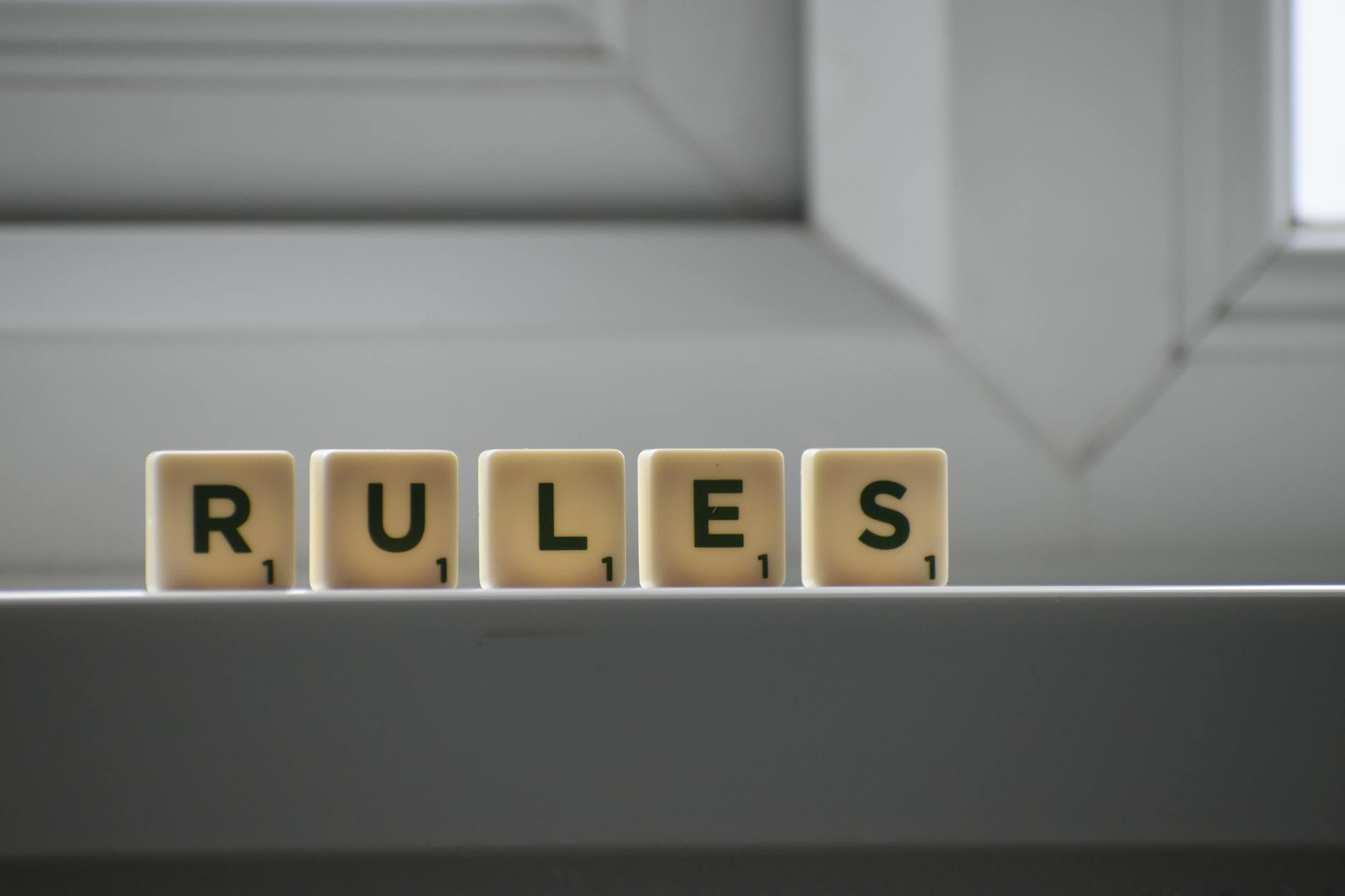 Five pieces from the board game 'Scrabble' that spell the word "Rules". /end